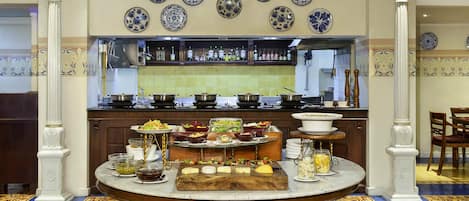A dining area with a round table, a bar in the background, and decorative plates on the wall.