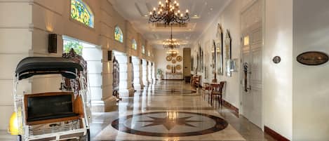A grand hotel lobby with a marble floor, chandeliers, and a carriage.