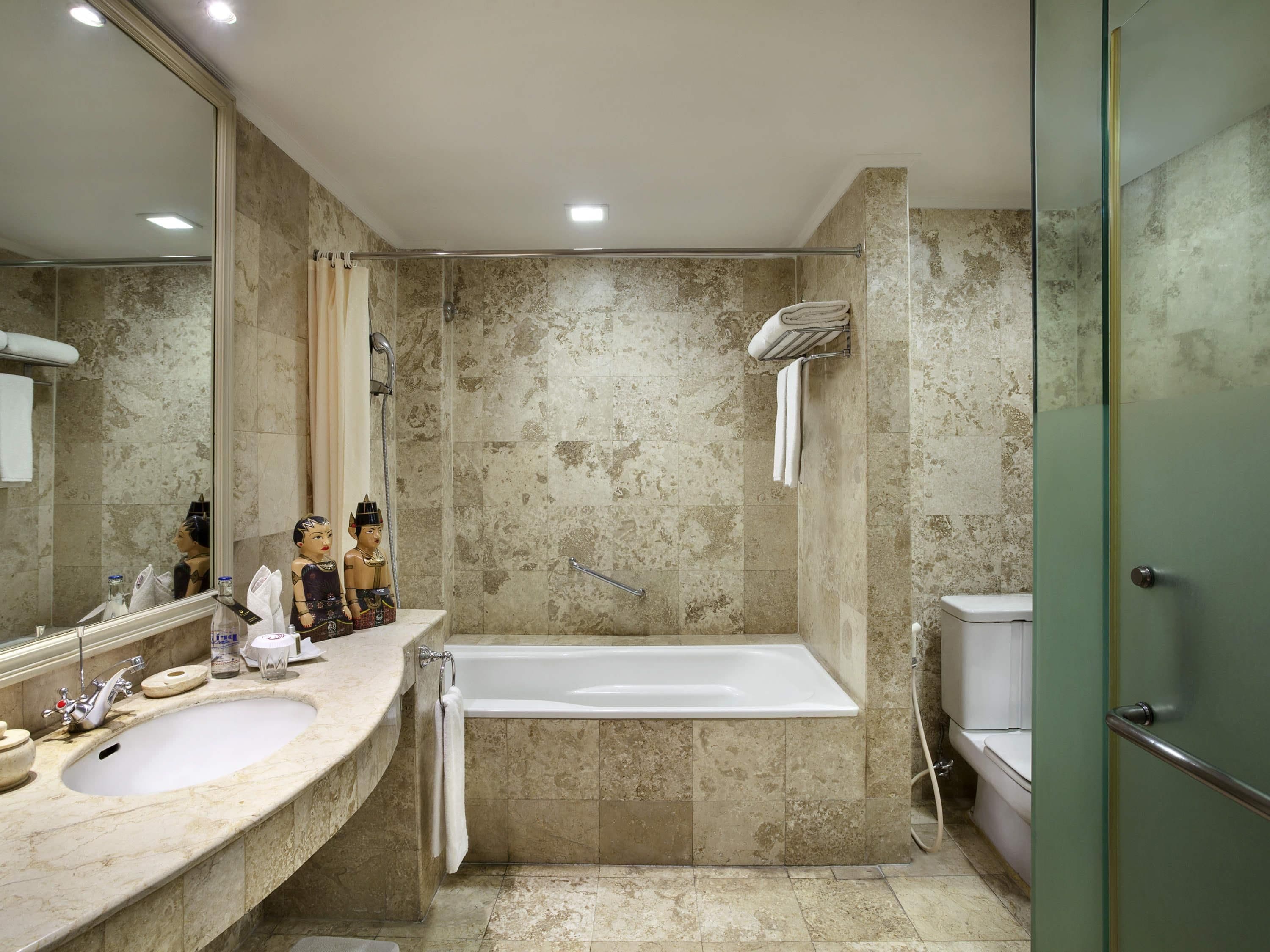 Un baño moderno con un espejo grande, una bañera y una zona de ducha.
