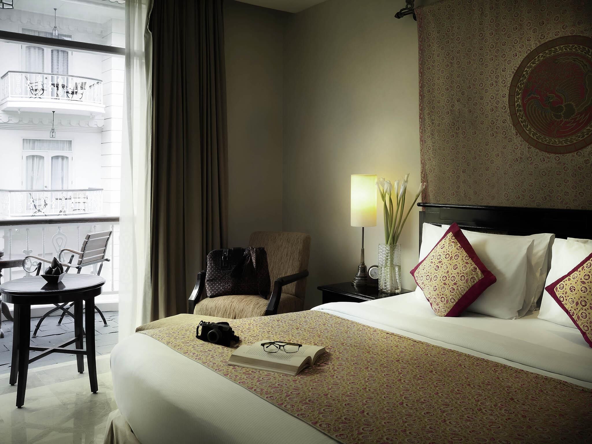 Une chambre d’hôtel avec un lit, un bureau, une chaise, une lampe et une vue sur la ville.
