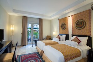 A hotel room with two beds, a TV, a desk, and a view of the outdoors. - The Phoenix Hotel Yogyakarta - Handwritten Collection (Yogyakarta)