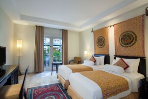 A hotel room with two beds, a TV, a desk, and a view of the outdoors.