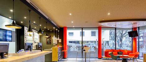 A modern interior with a reception desk, seating area, and large windows.