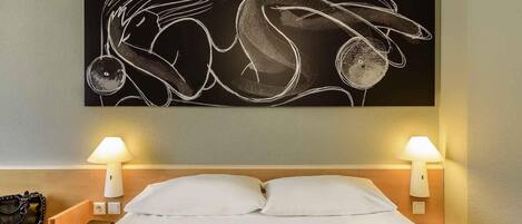 Habitación de hotel con cama, dos lámparas de noche, una mesita de noche con lámpara, un bolso y una obra de arte en la pared.