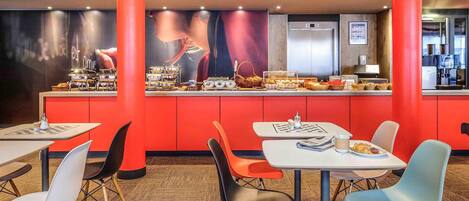 A modern restaurant with red accents, featuring a buffet with various dishes and a large mural on the wall.