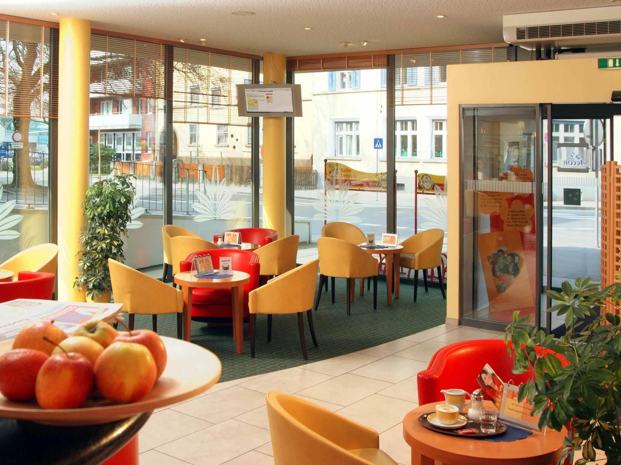 A cafe with yellow chairs, a table with apples, and a TV screen.