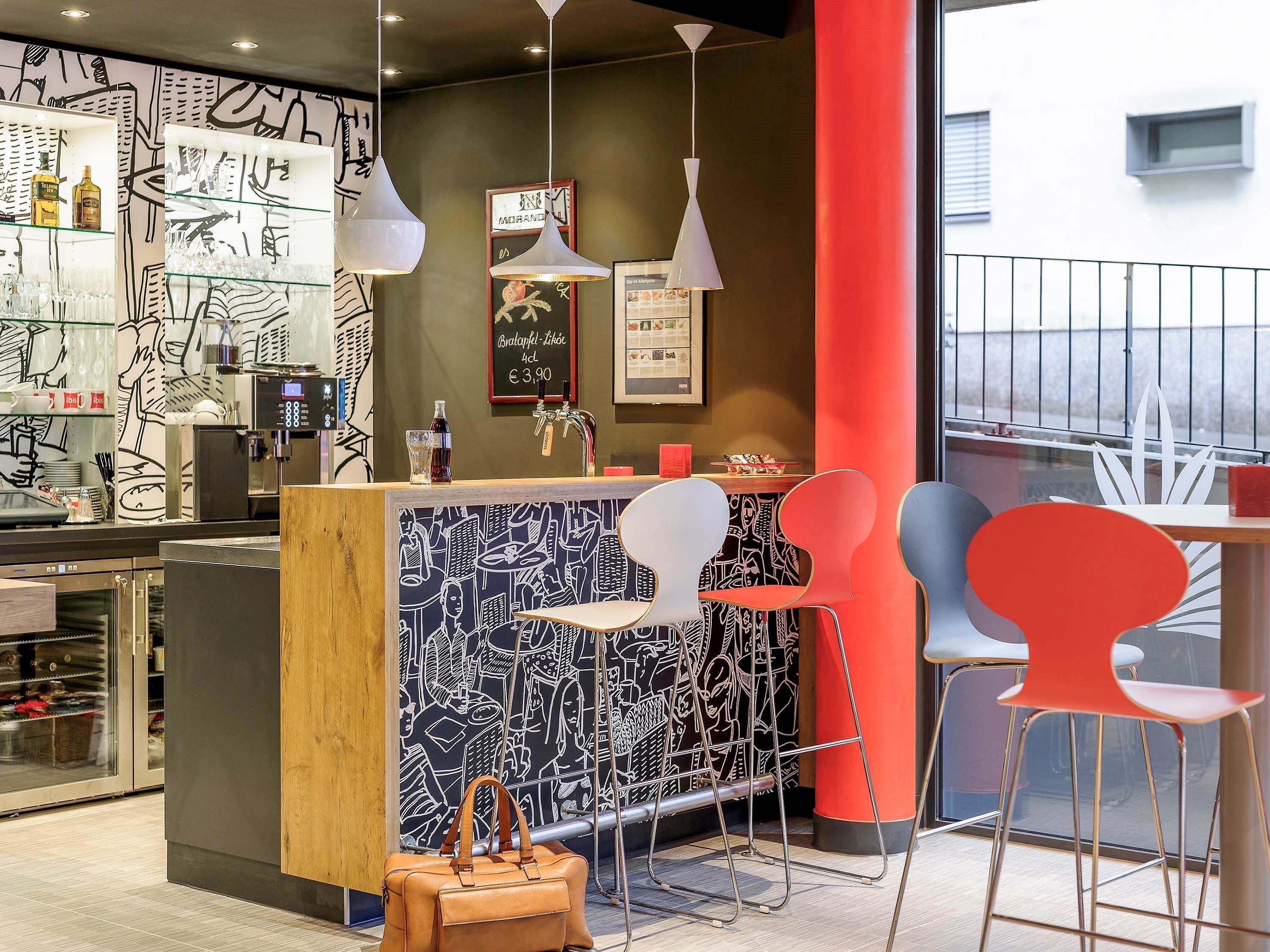 Un espace bar avec un comptoir, des tabourets et un mur orné d’œuvres d’art abstraites.