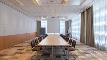 A conference room with a long table, chairs, a projector screen, and a whiteboard.