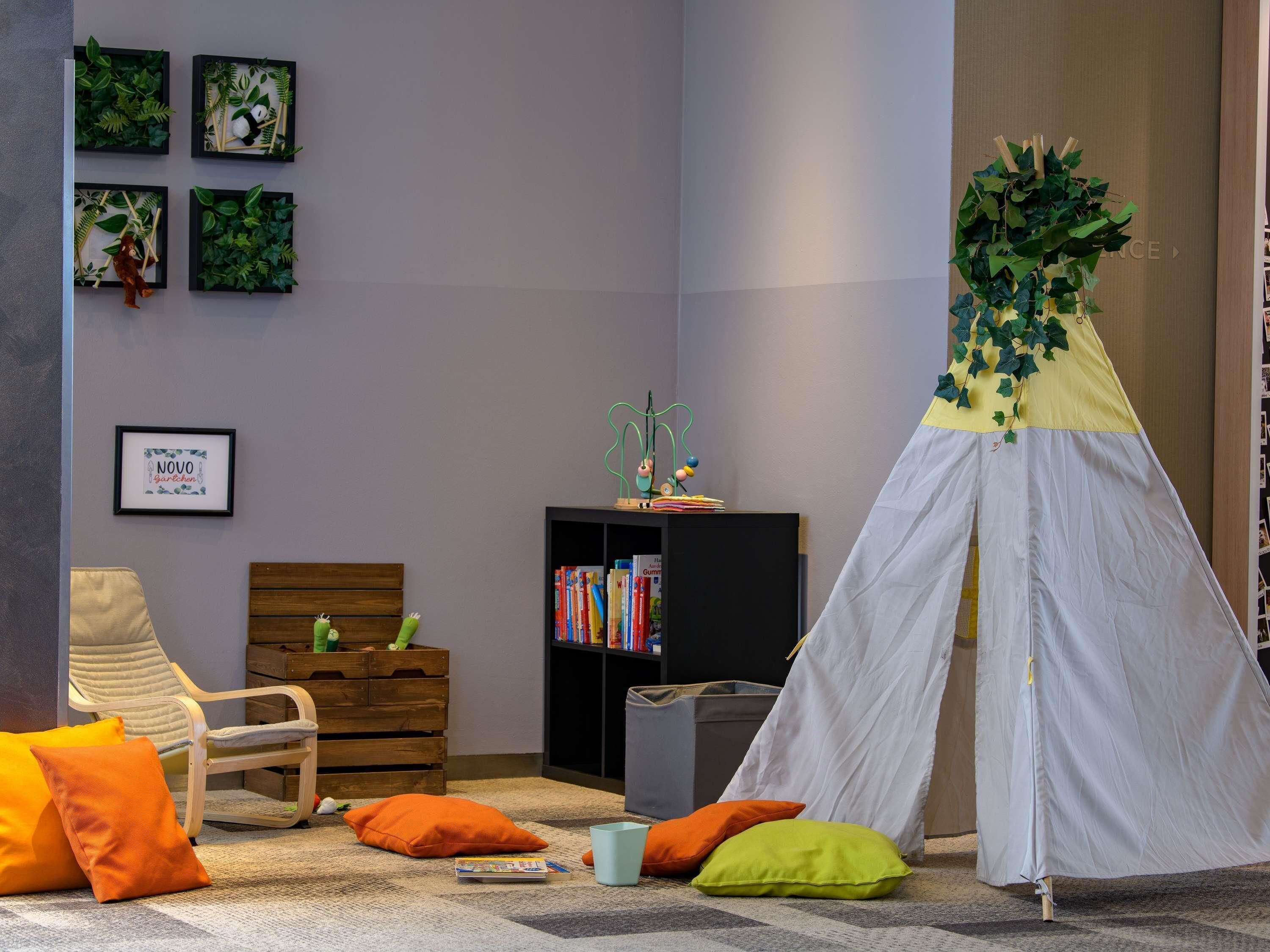 Een gezellige kamer met een houten stoel, een klein boekenkastje en een witte, tentachtige constructie met begroeiing.
