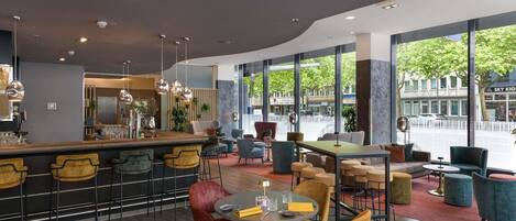 A modern bar area with seating, large windows, and a view of the street.