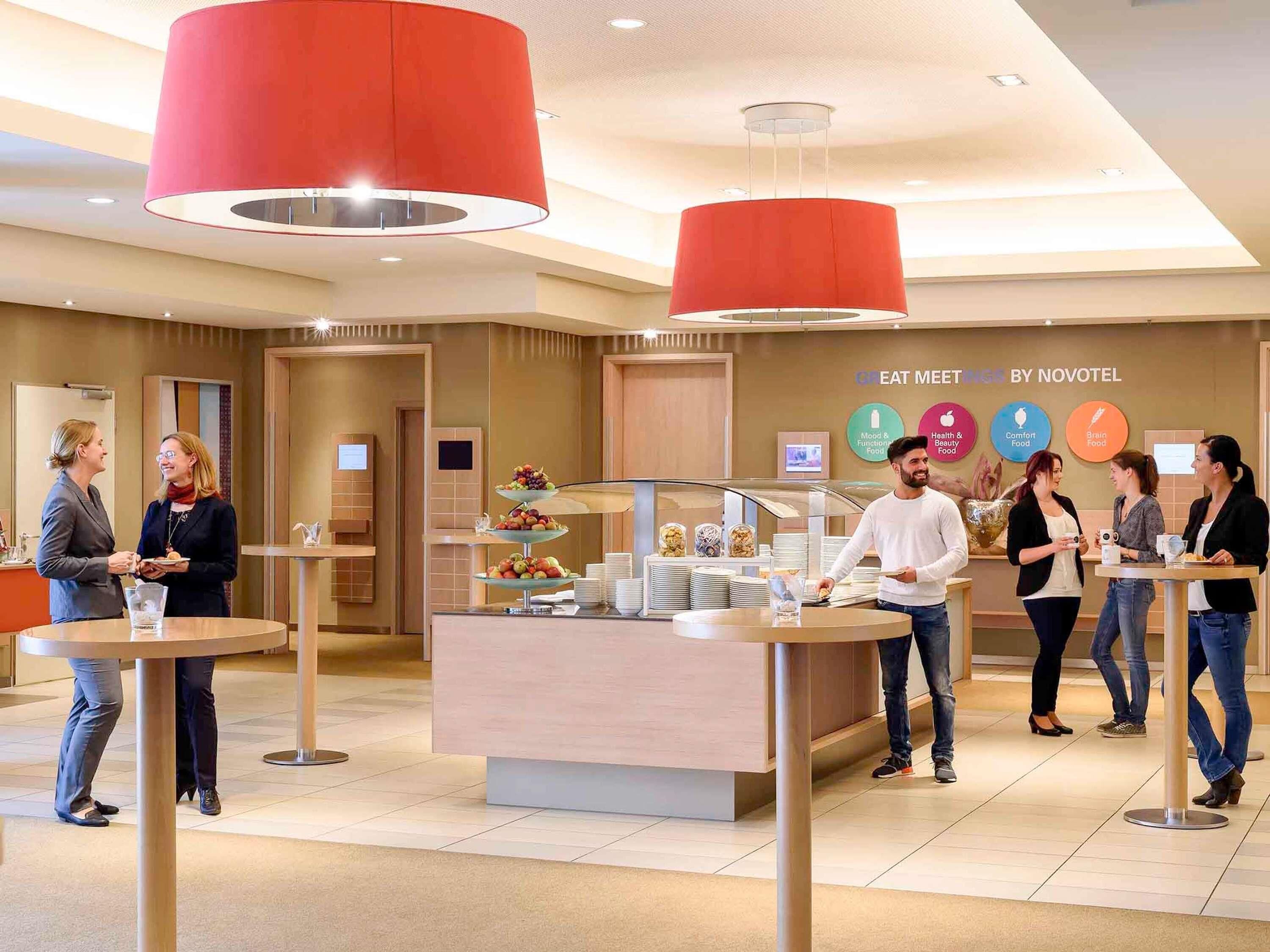 A modern hotel lobby with a buffet area, a reception desk, and a wall displaying the hotel's name and services.