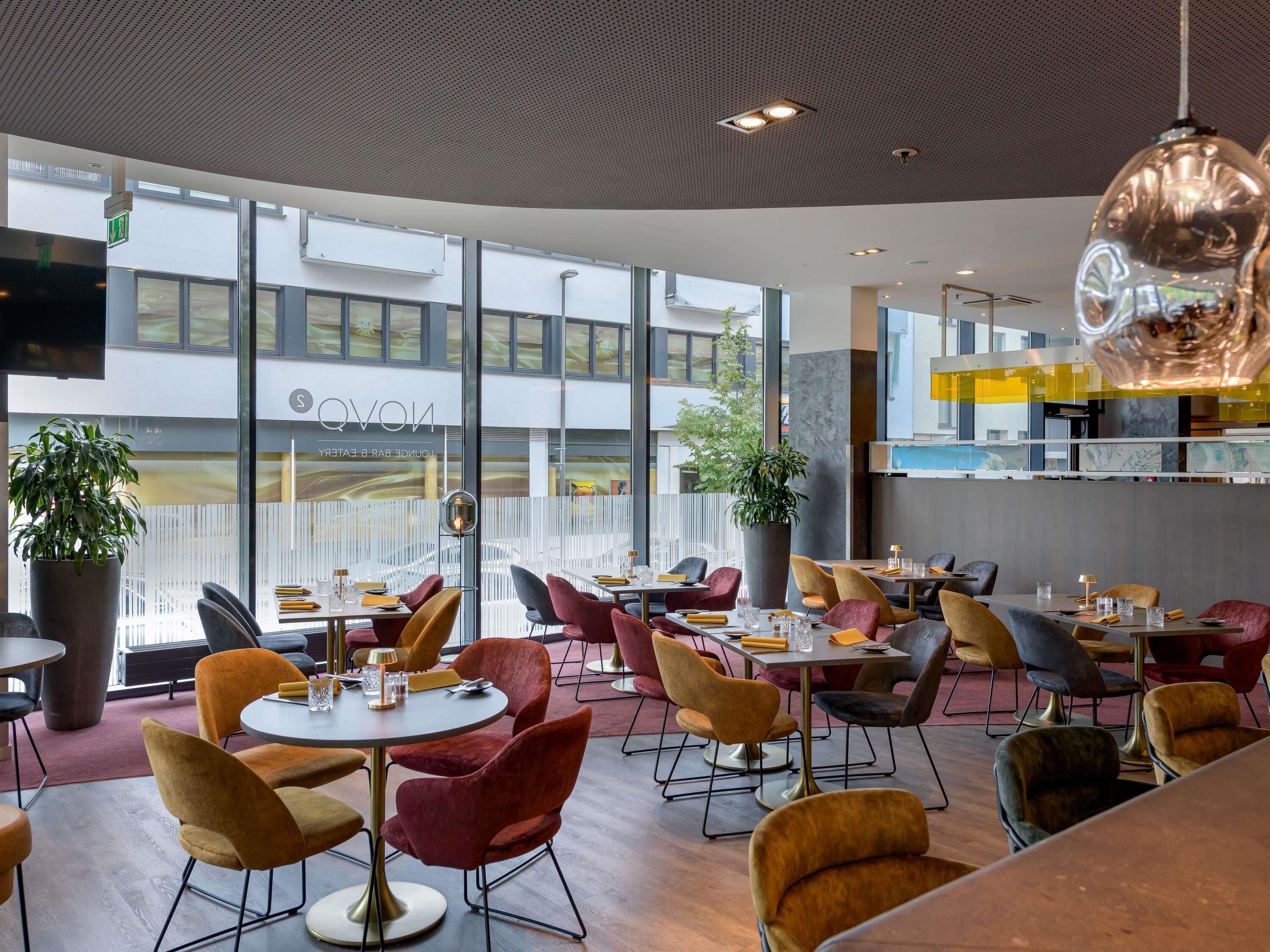 A modern restaurant interior with round tables, plush chairs, and large windows.