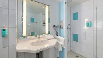 A modern bathroom with a large mirror, sink, and shower.