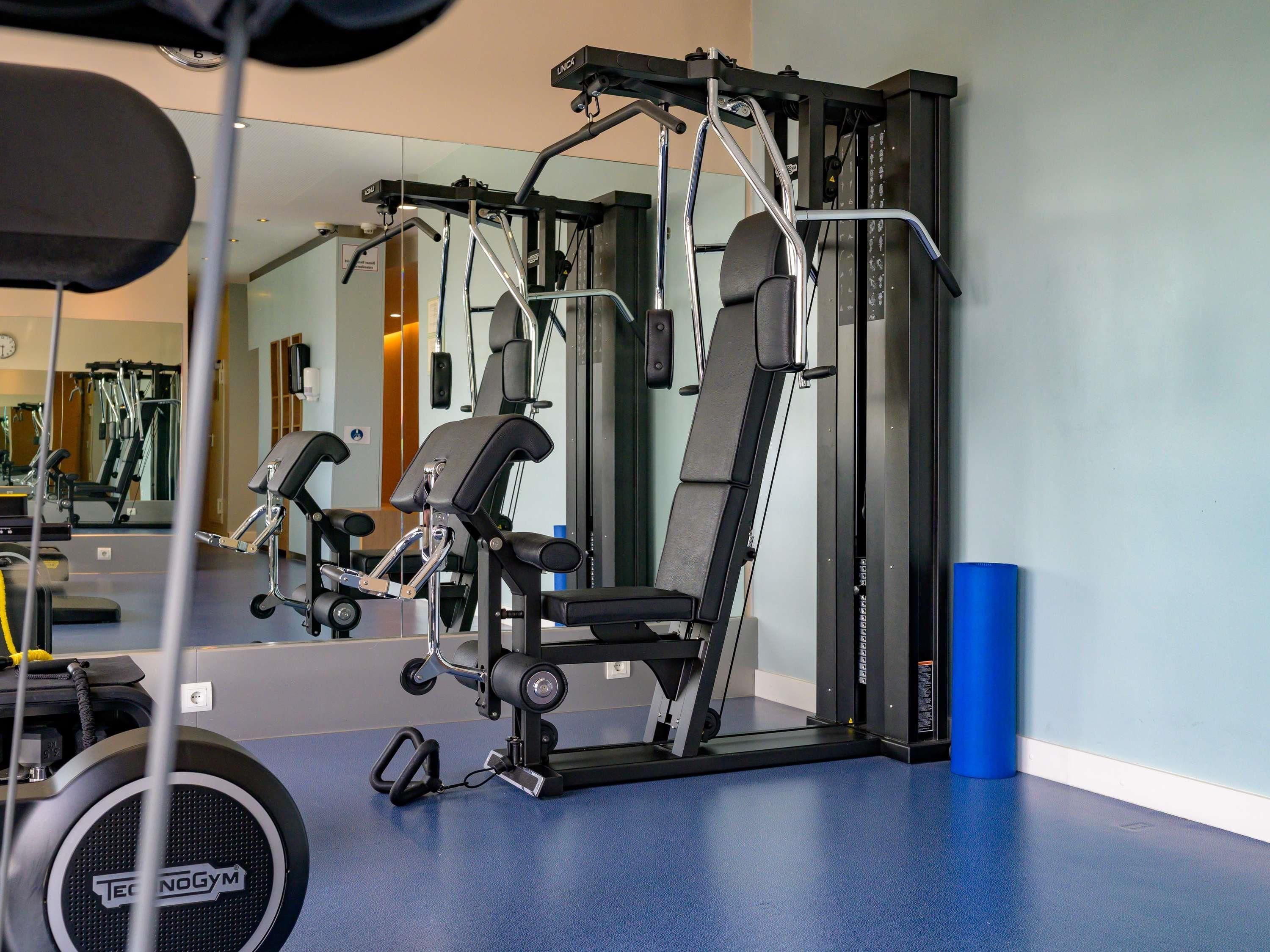 A gym with exercise equipment, a mirror, and a blue mat.