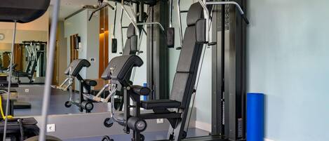 A gym with exercise equipment, a mirror, and a blue mat.