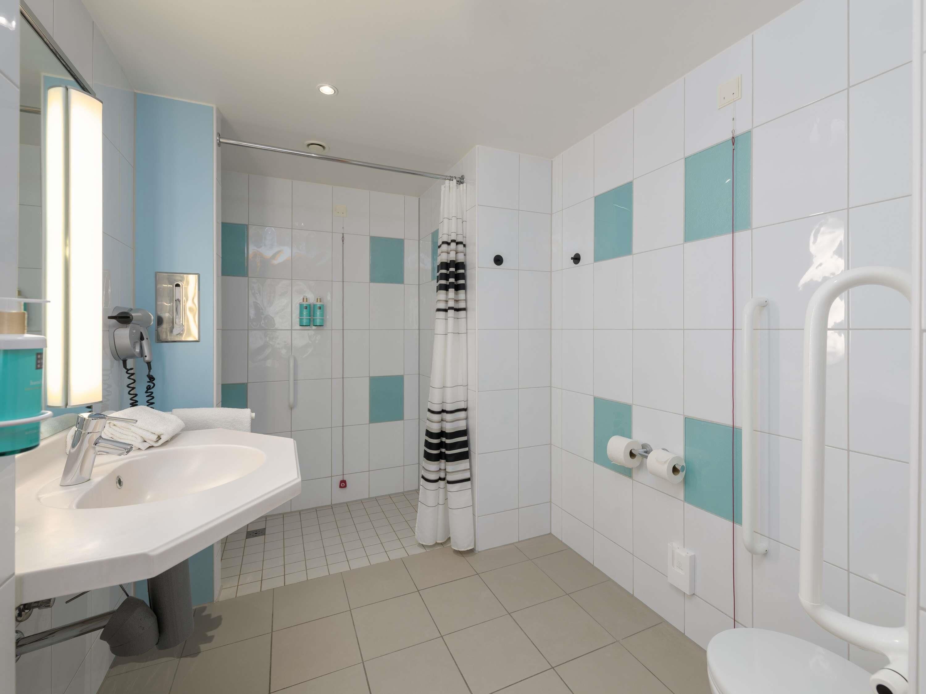 A bathroom with a sink, mirror, shower, and toilet.