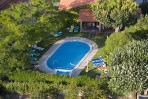 An aerial view of a swimming pool surrounded by green lawns and trees, with lounge chairs and a small pavilion. - Alegre - Bussaco Boutique Hotel (Mealhada)