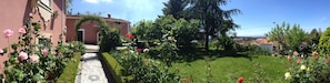 Un jardín con un sendero empedrado que conduce a un edificio de fachada roja.