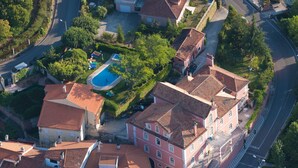 Vista aérea de una zona residencial con piscina, rodeada de casas con tejados de tejas rojas.