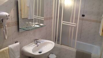 A bathroom with a sink, mirror, and a hairdryer on the wall.