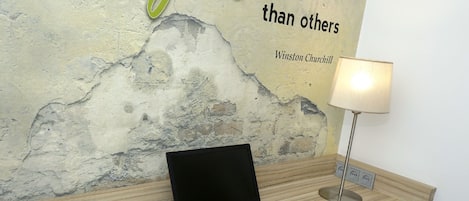 Ein hölzerner Empfangstresen mit einem Laptop, einer Maus und einer Lampe. Eine Broschüre liegt auf dem Tresen.