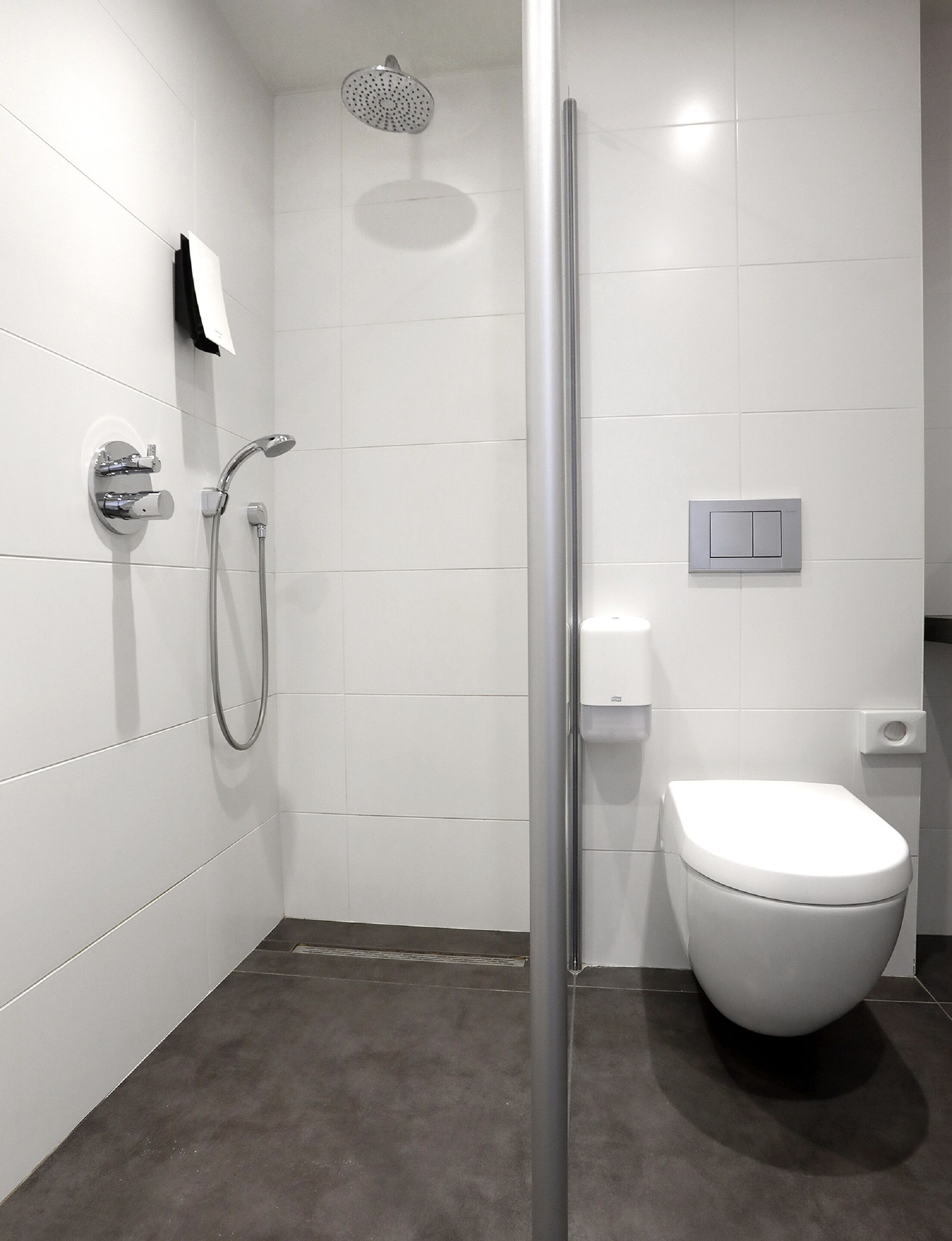 A modern bathroom with a shower, toilet, and a towel rack.