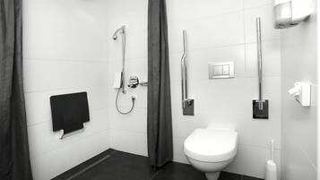 A modern bathroom with a shower, toilet, and hand dryer.