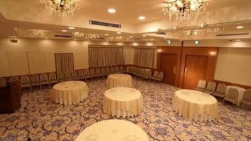 A conference room with round tables, a chandelier, and a patterned carpet.