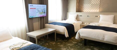 Une chambre d’hôtel avec deux lits, un bureau et un téléviseur affichant un plan de l’hôtel.