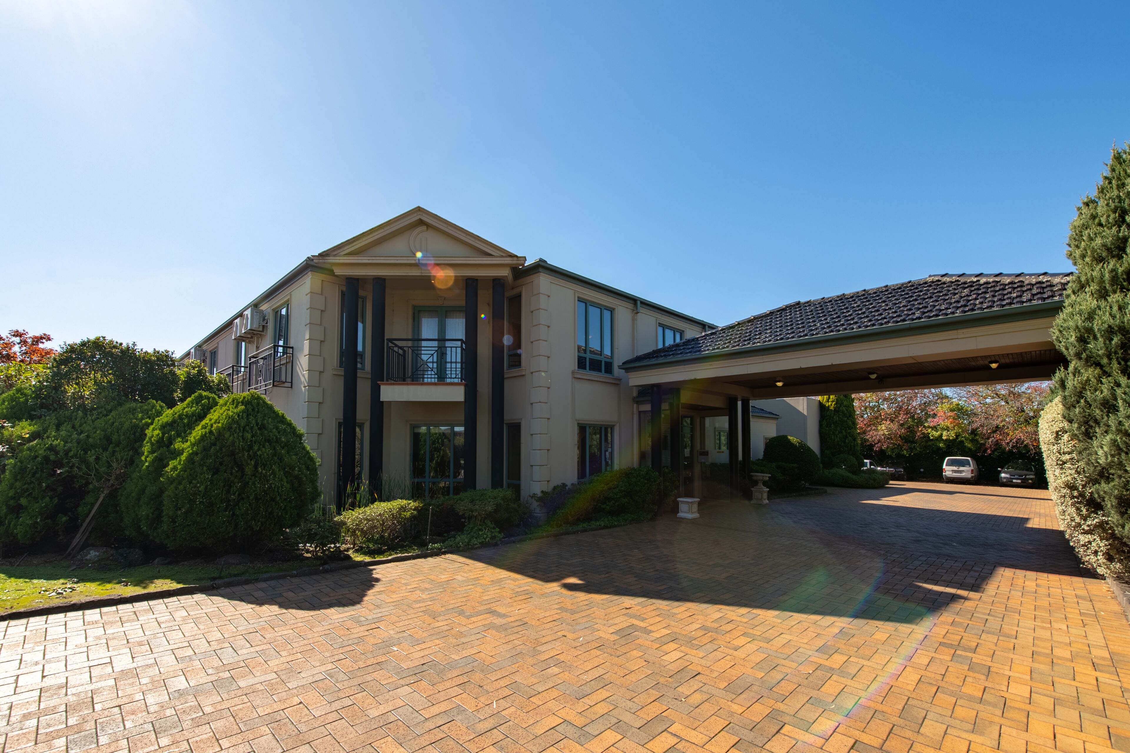 A two-story house with a covered driveway and a large front lawn.