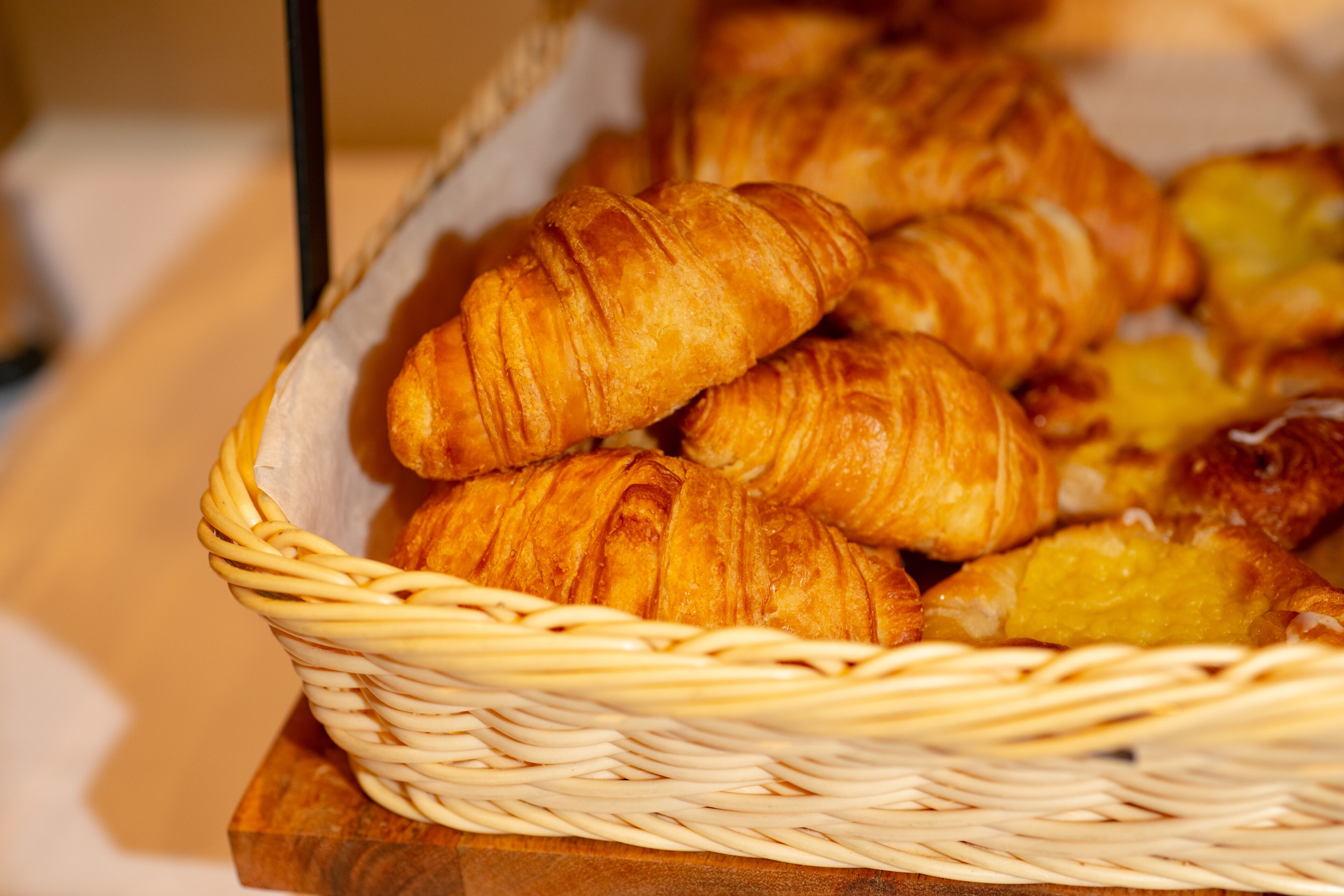 Una cesta con croissants sobre una superficie de madera.