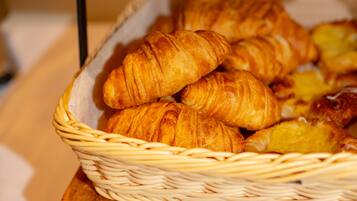 Una cesta con croissants sobre una superficie de madera.