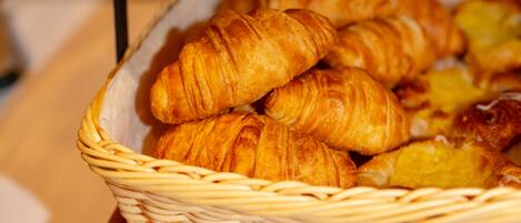 A basket of croissants on a wooden surface.