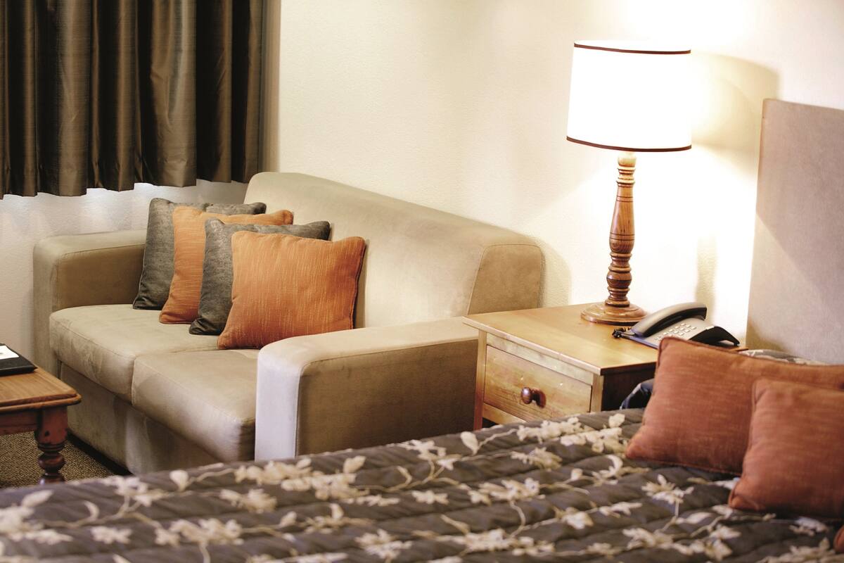 Une chambre d’hôtel comprenant un lit, un canapé, une table de chevet avec une lampe et un téléphone.