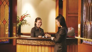 A reception desk with a wooden counter and a vase of flowers.