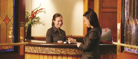A reception desk with a wooden counter and a vase of flowers.