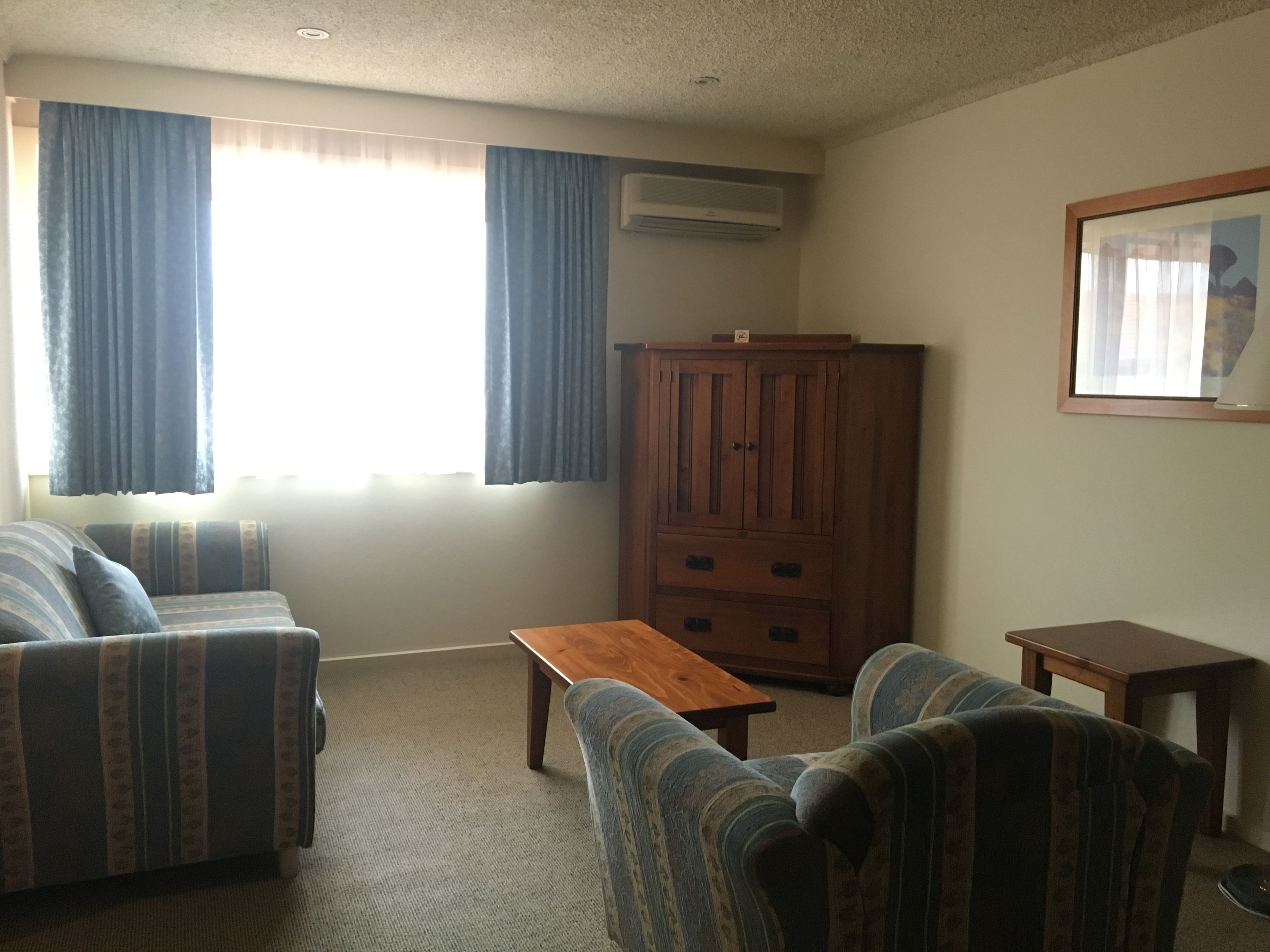 A living room with two striped sofas, a wooden table, and a cabinet.