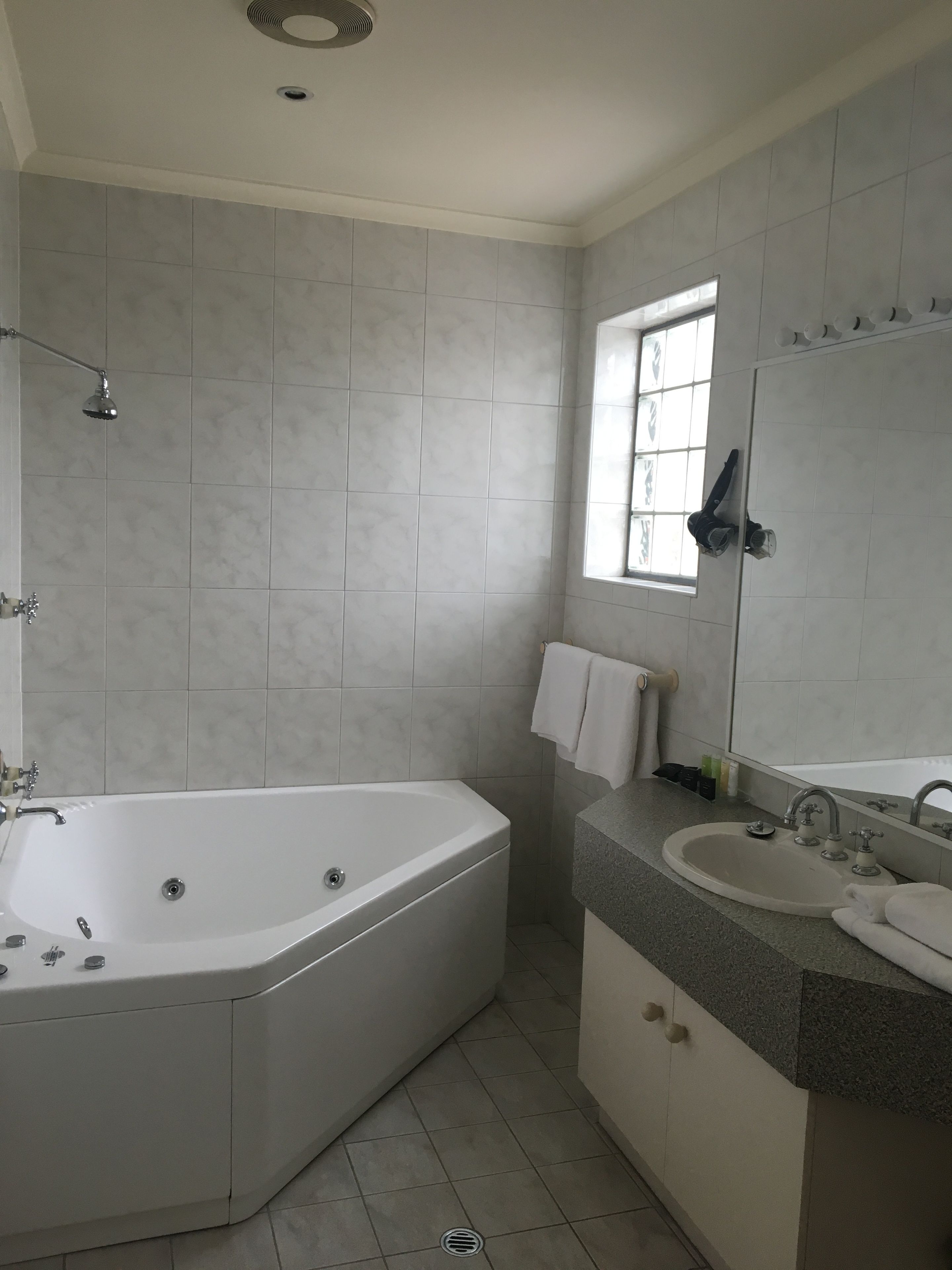 A modern bathroom with a freestanding bathtub, a sink with a mirror, and a window providing natural light.