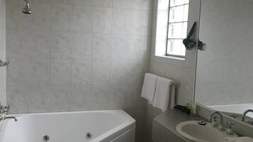 A modern bathroom with a freestanding bathtub, a sink with a mirror, and a window providing natural light.