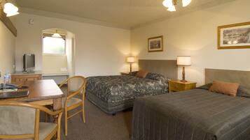 A hotel room with two beds, a desk with a chair, a television, and a window.
