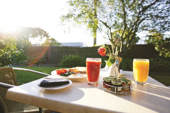 A table with a glass of orange juice, a glass of red juice, and a plate of food.