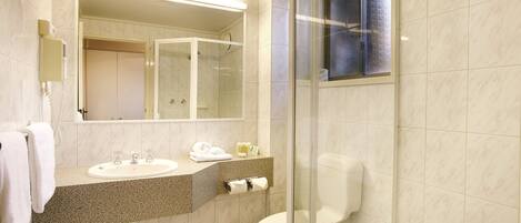 A modern bathroom with a glass shower enclosure, a sink with a towel, and a toilet.