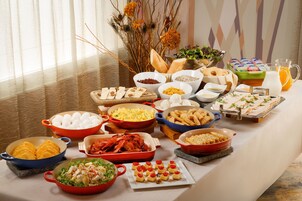 A buffet table with various food items and a pitcher of orange juice.
