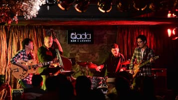 A band performing on a stage with a sign that reads "dada BAR + LOUNGE".