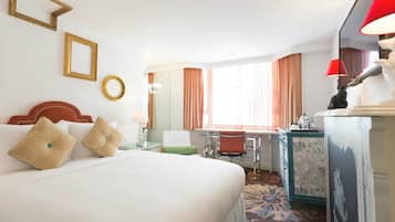 Une chambre d’hôtel avec un grand lit, un bureau, une chaise et une commode.