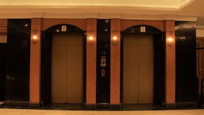 A set of three elevators with a classic design, featuring a central control panel and two side panels with light fixtures.