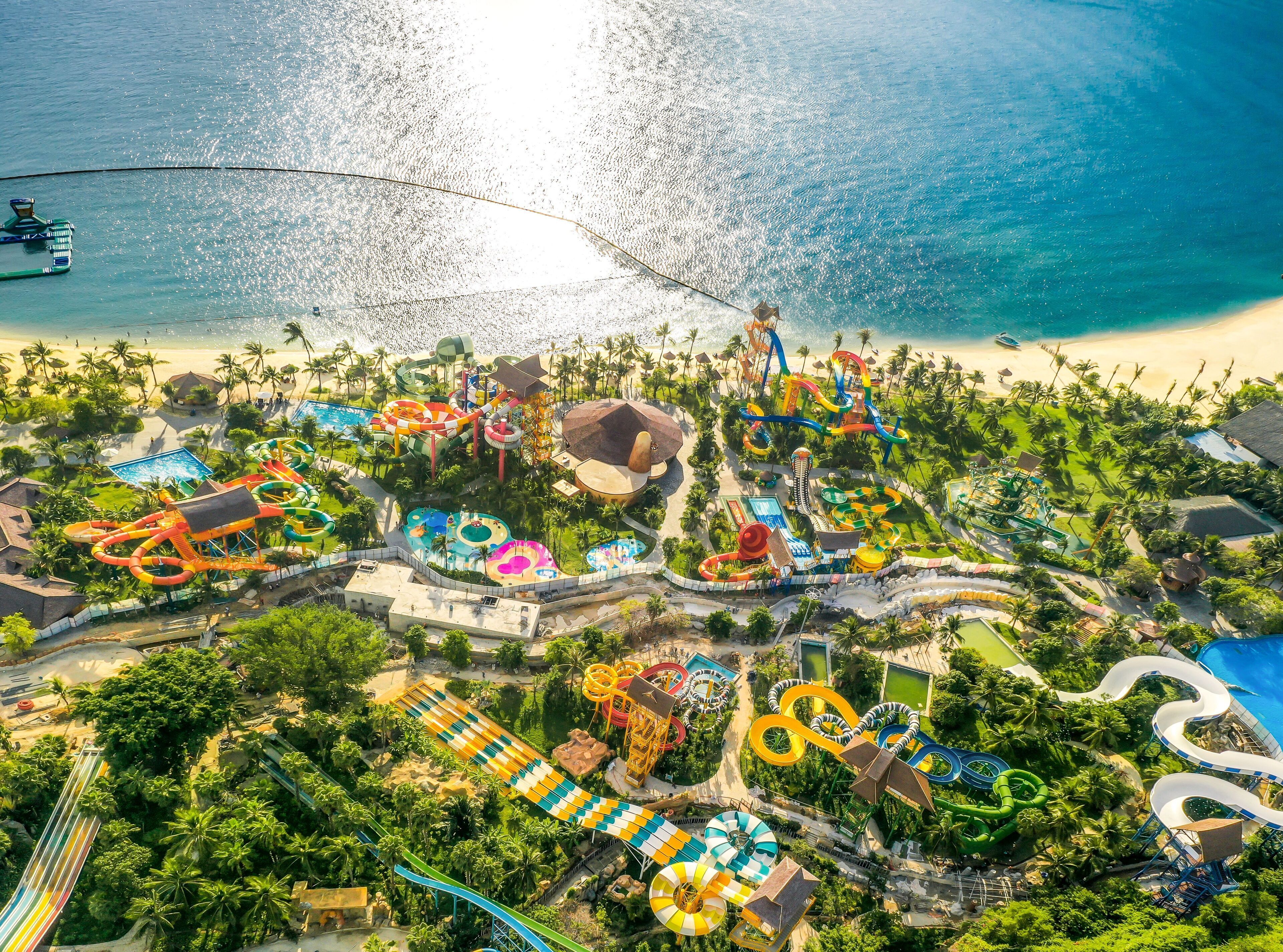 Vista aérea de un resort con parque acuático, playa y palmeras.