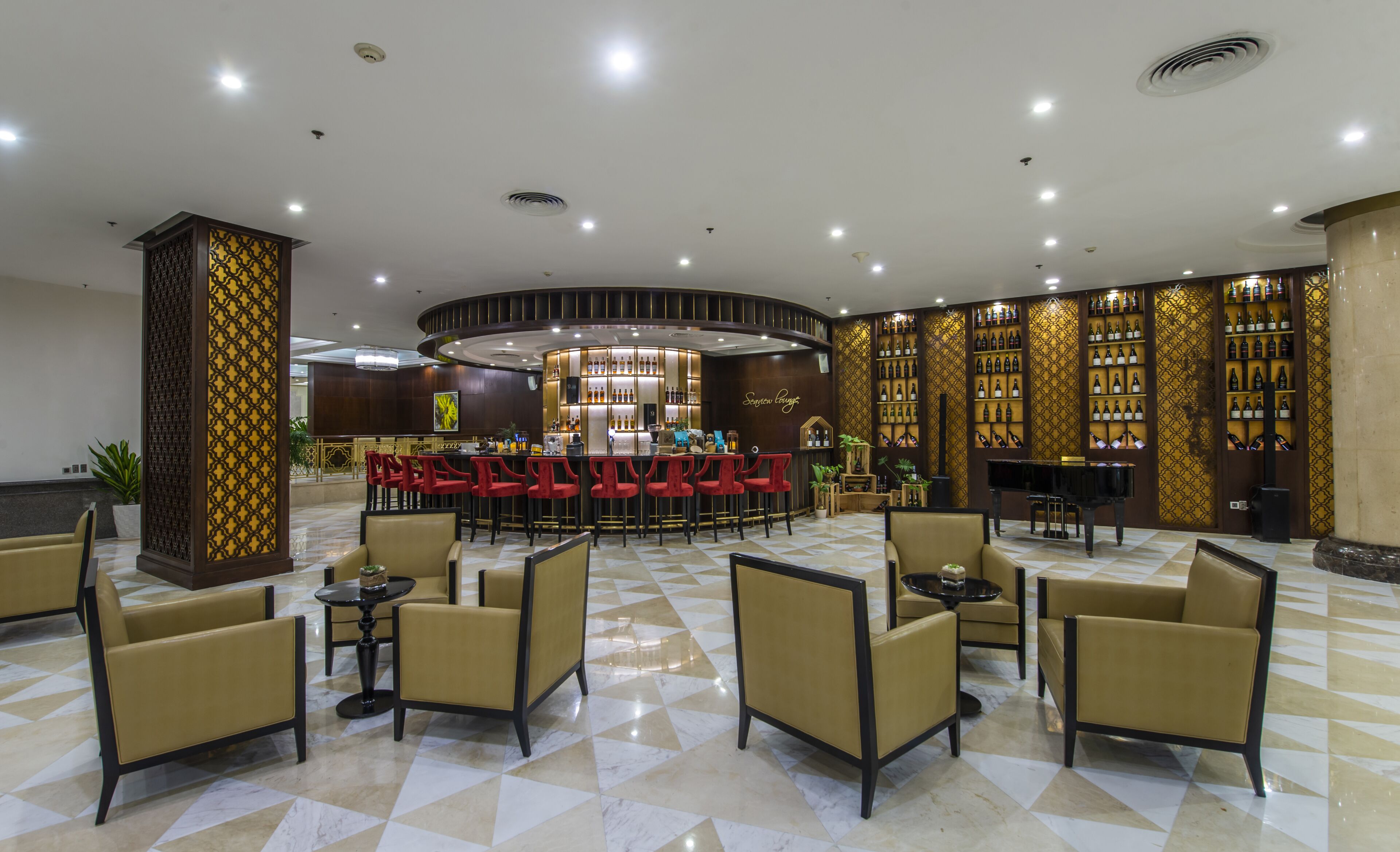 A spacious lobby with a bar area, seating arrangements, and a piano.