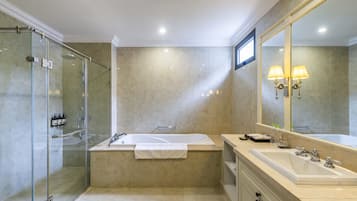 A modern bathroom with a glass-enclosed shower, a freestanding bathtub, and a large vanity with a mirror.