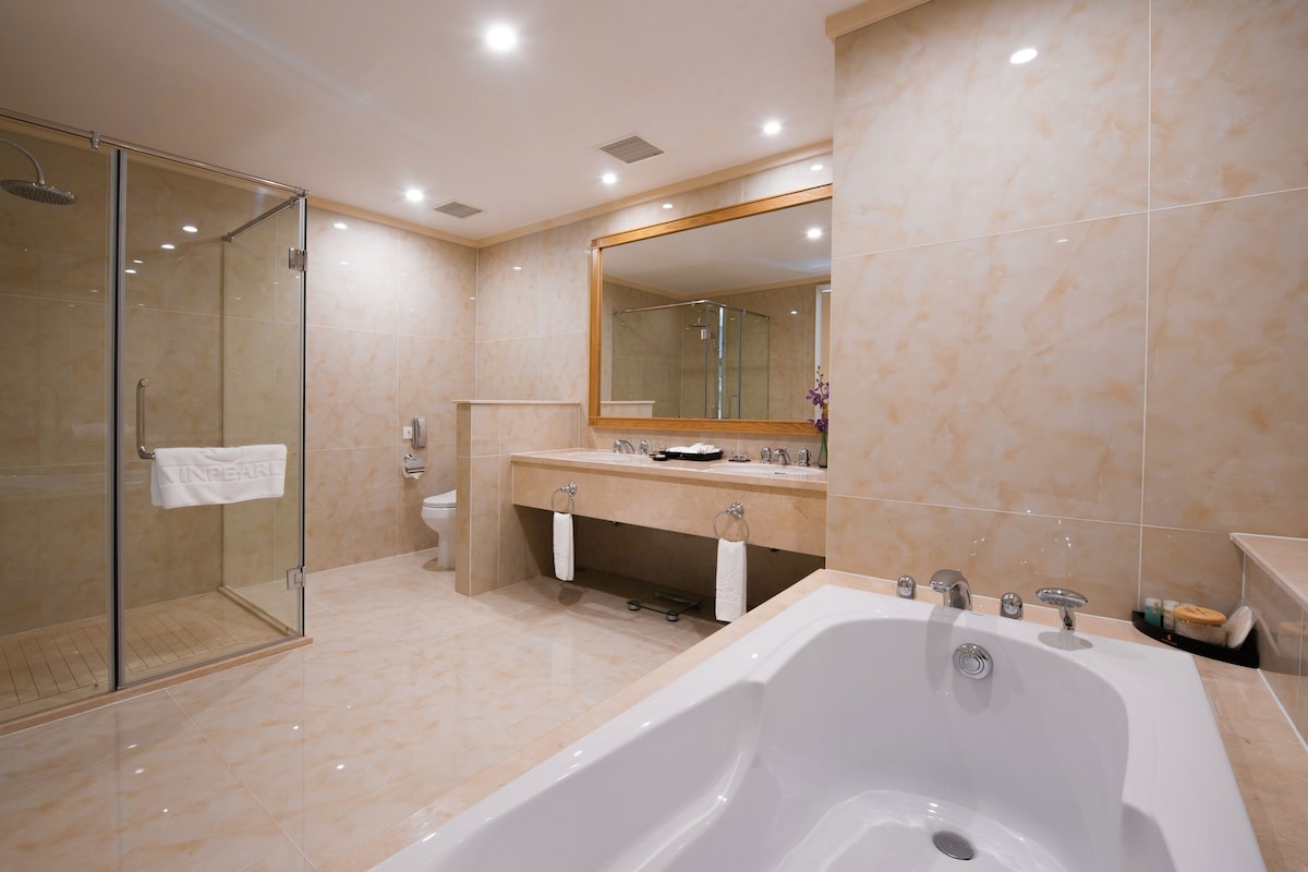 Une salle de bain moderne dotée d’une douche à parois de verre, d’une grande baignoire et d’un meuble-lavabo avec un miroir.